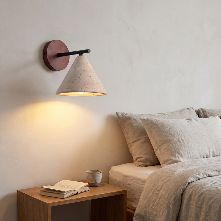 Thea wall sconce lit beside a bed