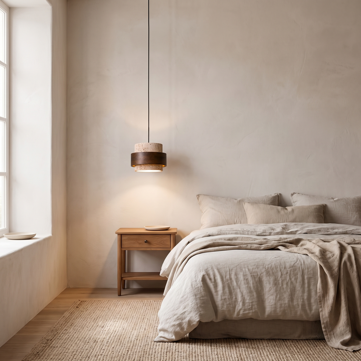 A single Juno pendant light hanging above a nightstand beside a bed