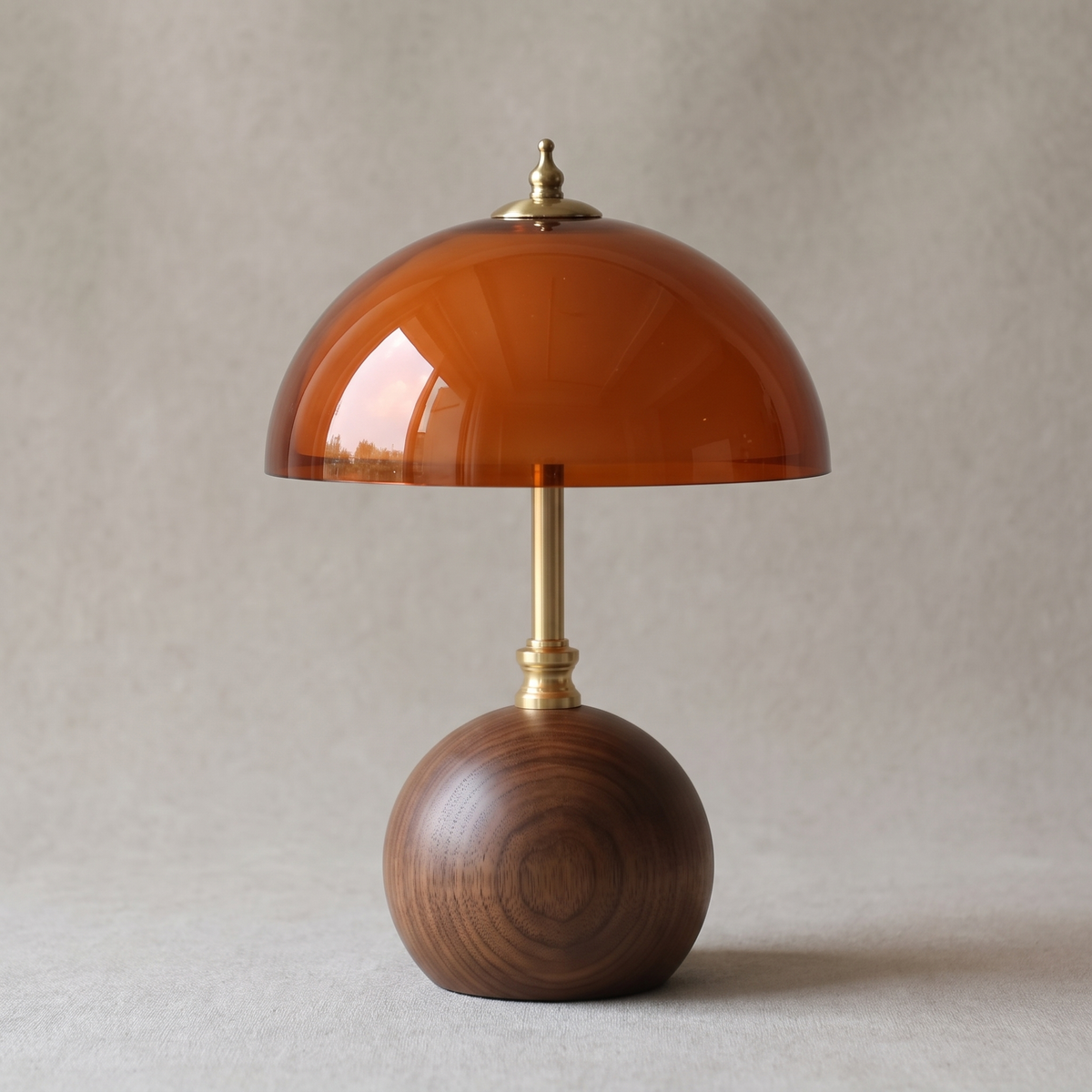 Close view of the walnut sphere base, brass stem and amber dome of the Cleo lamp