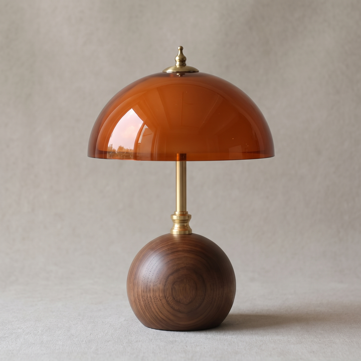 Close view of the walnut sphere base, brass stem and amber dome of the Cleo lamp