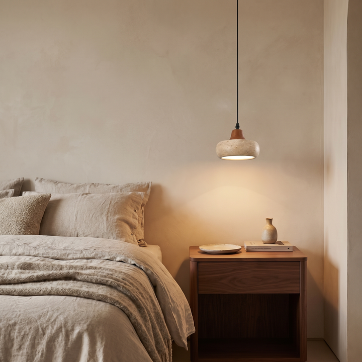 Freya travertine and walnut pendant lit above a bedside table