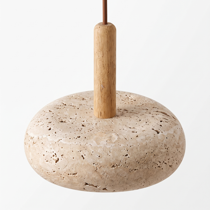 Close view of the pitted travertine disc and wood stem of the Maeve pendant