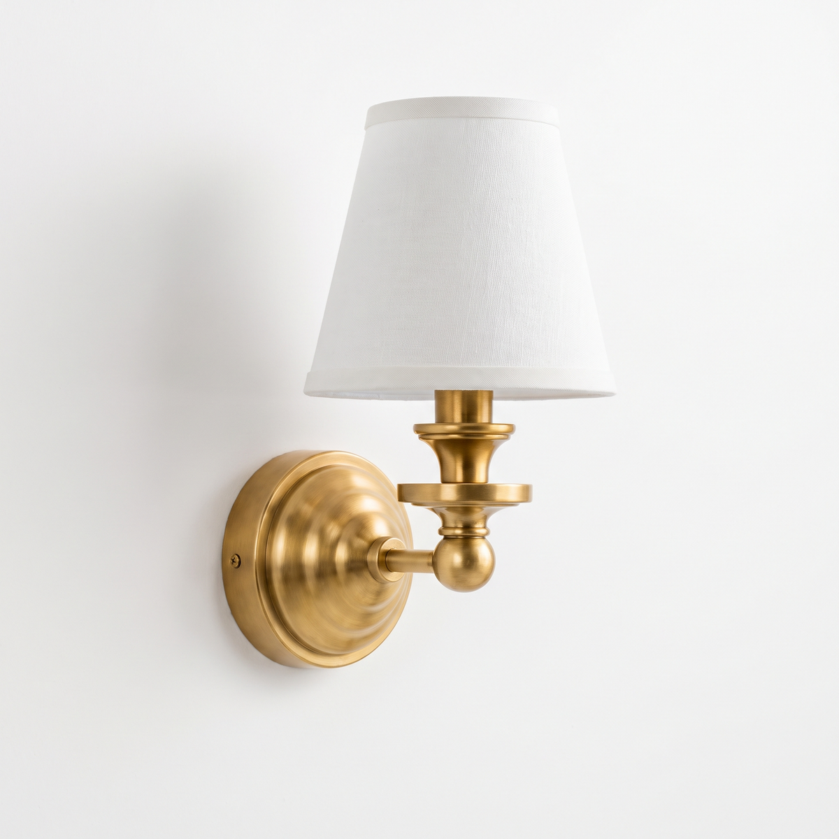 Elsie linen shade wall sconce in antique brass on a white background
