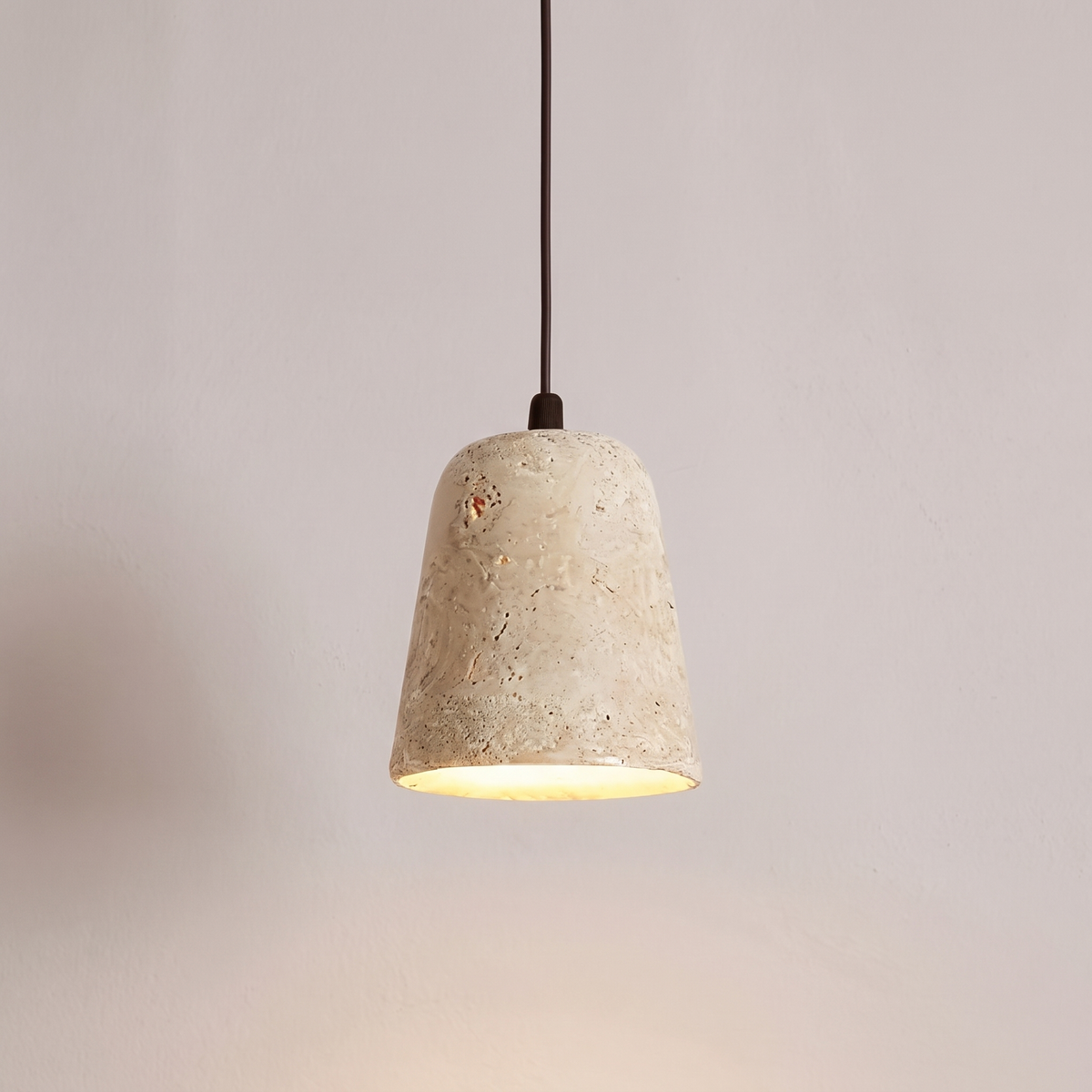 Close view of the pores and bell shoulder of the Signe travertine pendant