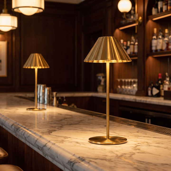 Two Isla brass cordless lamps lit on a marble bar counter