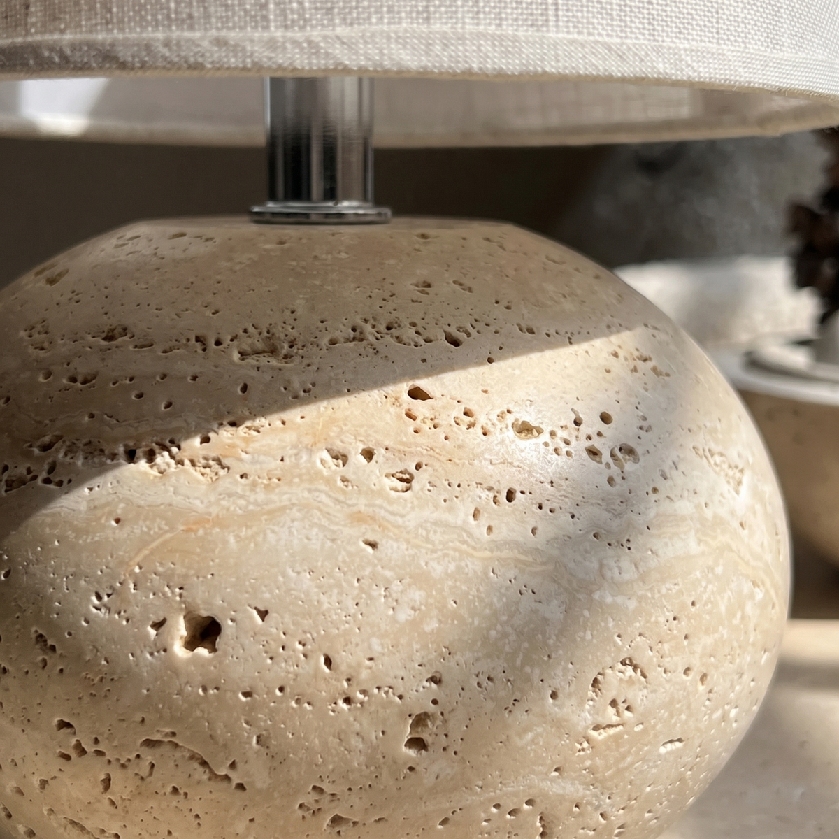 Close view of the pitted travertine sphere base of the Nella lamp