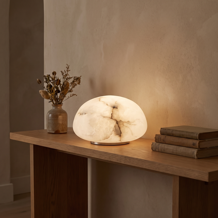Tove low dome alabaster lamp lit on a hallway console at dusk