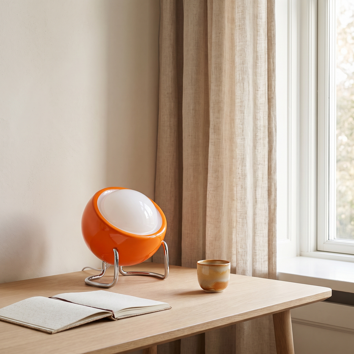 Ines orange open globe table lamp on an oak desk by a window