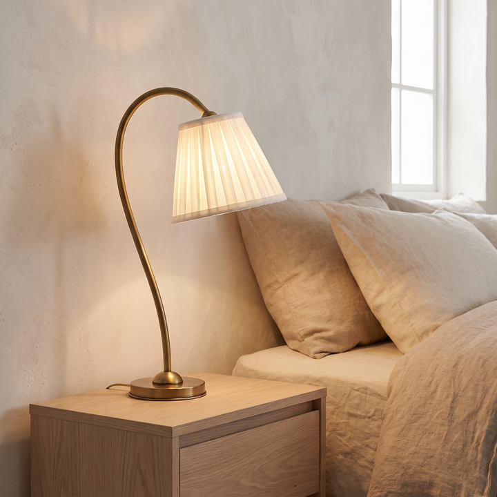 Marit pleated linen table lamp lit on an oak bedside table