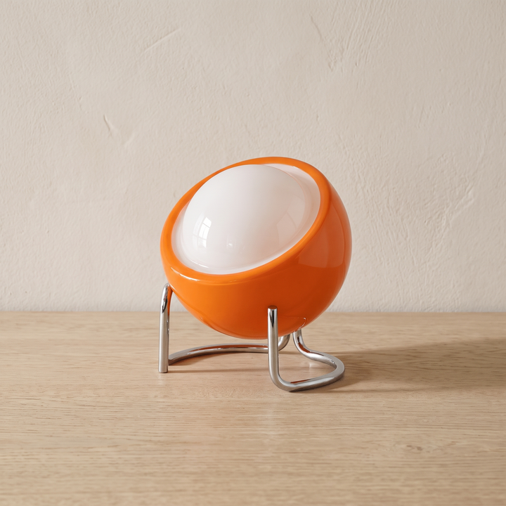 Ines open globe table lamp in orange glass on a chrome tripod