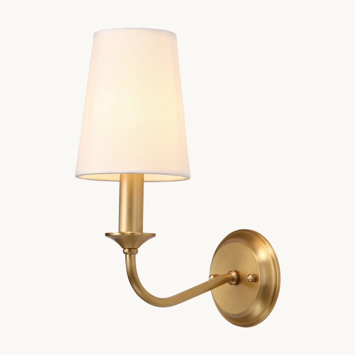 Brienne brass arm and fabric shade wall light on white studio background