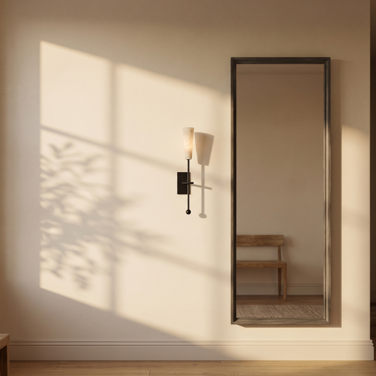 Tessara Torch wall sconce in black beside a framed mirror at dusk