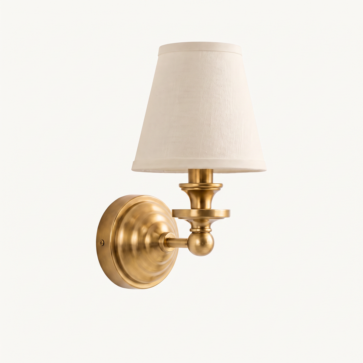 Elsie linen shade wall sconce in antique brass on a warm off white studio background