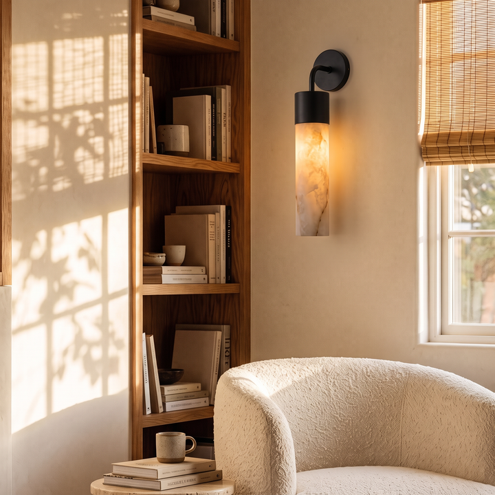 Tessara Long Tube slim marble wall sconce in matte black, lit beside shelving