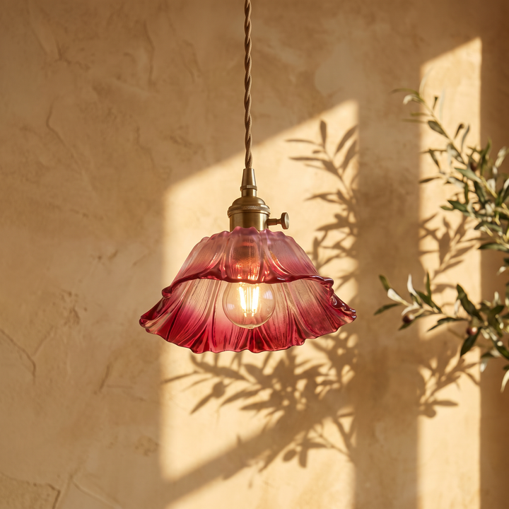 Fiorella petal glass cord pendant light in dusty mauve, lit against a plaster wall