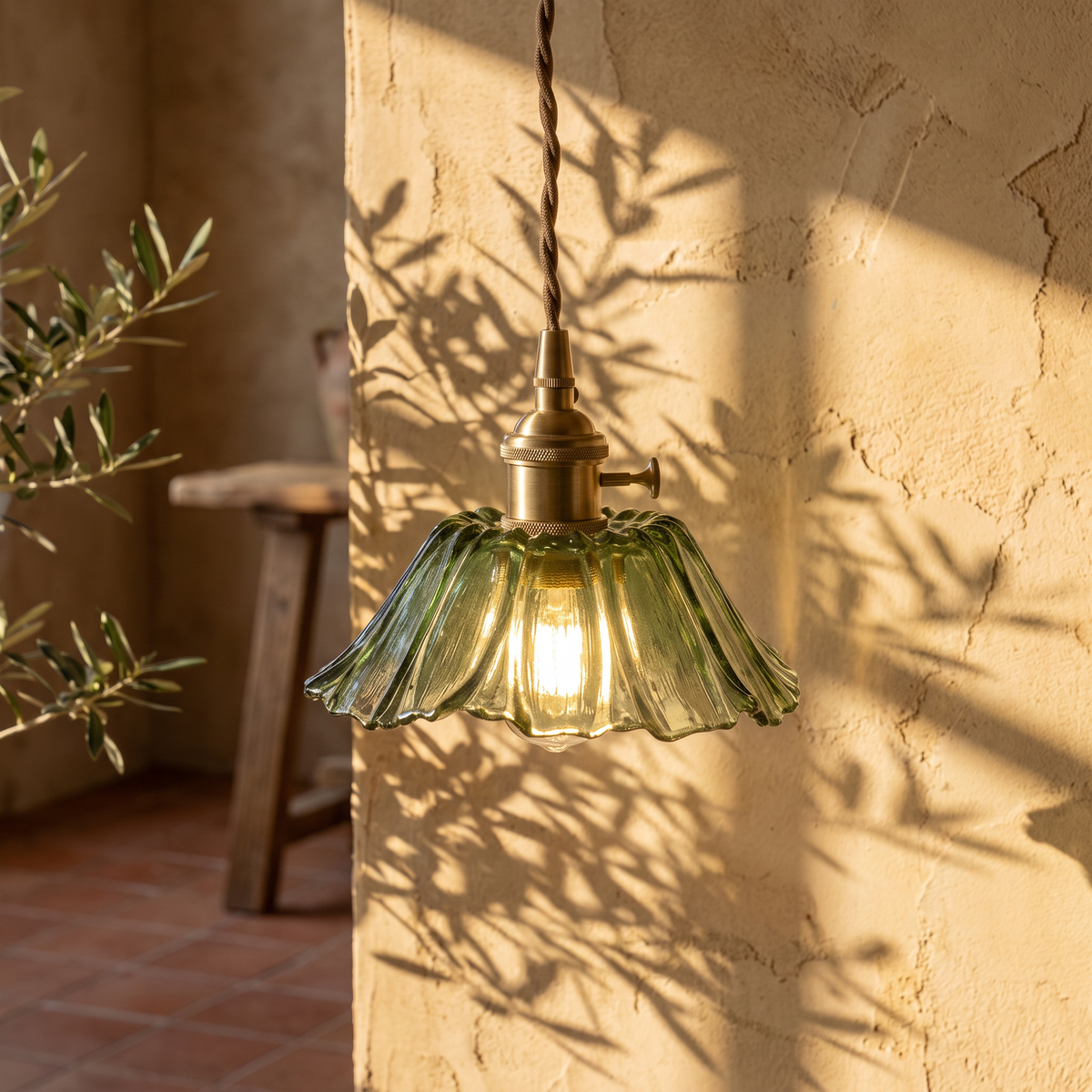 Fiorella petal glass cord pendant light in leaf green, lit against a plaster wall