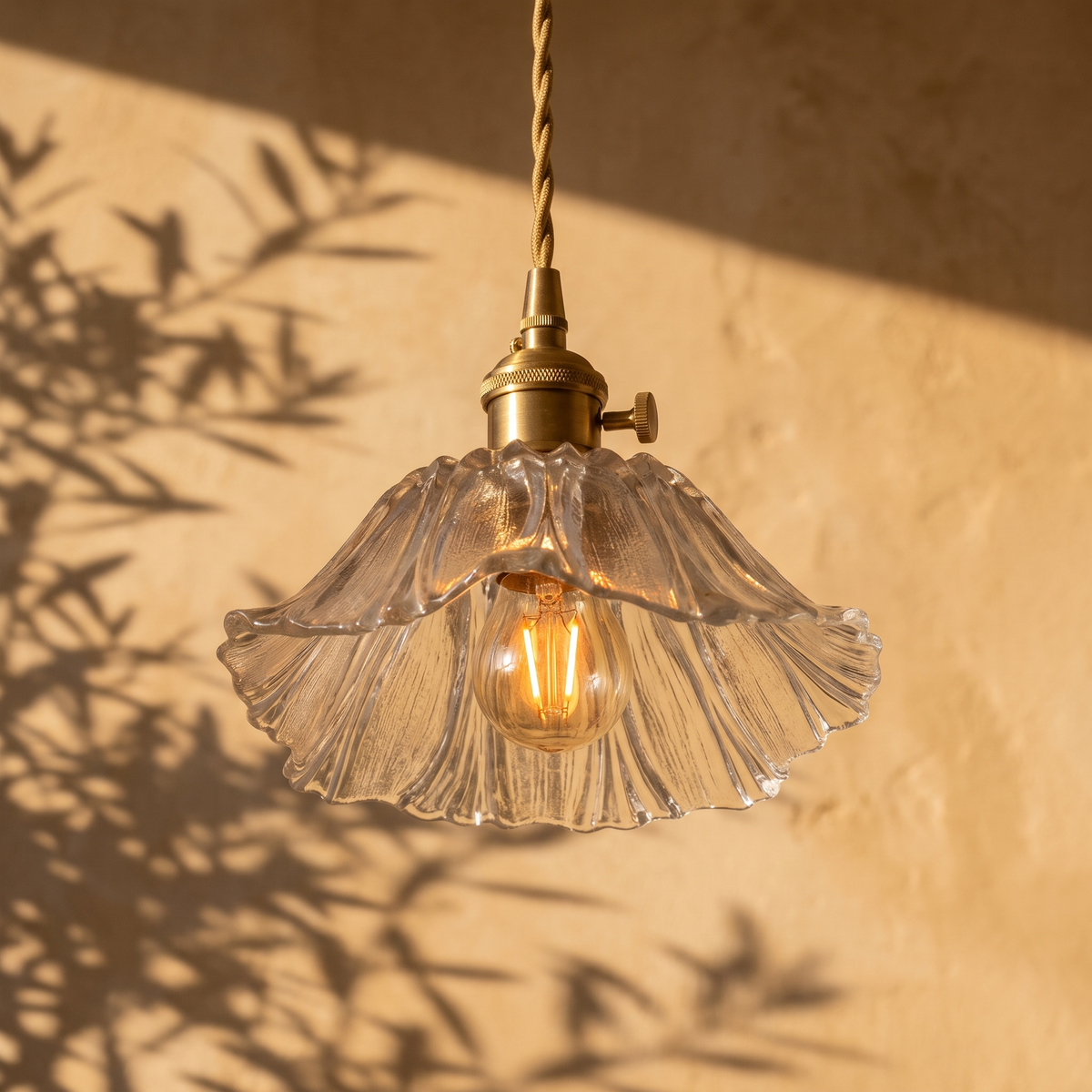 Fiorella petal glass cord pendant light in opal white, lit against a plaster wall