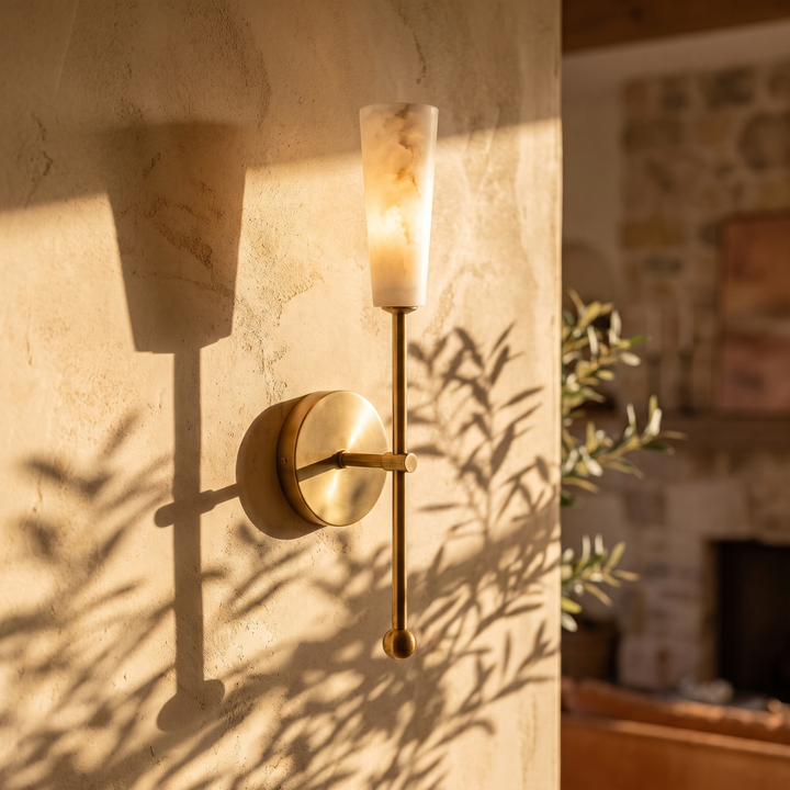 Tessara torch tall marble wall sconce in copper, lit on a plaster wall