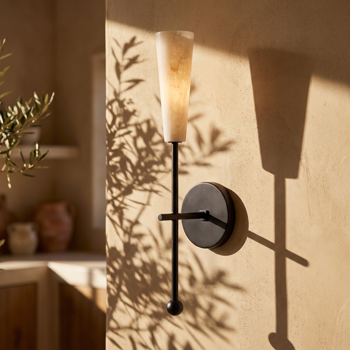 Tessara torch tall marble wall sconce in black, lit on a plaster wall