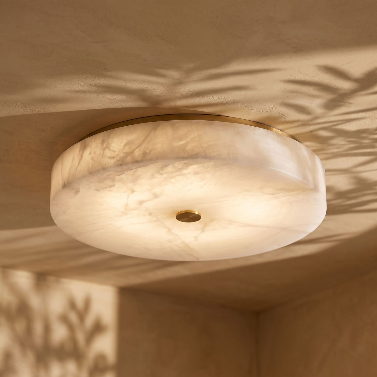 Lunetta marble and brass flush ceiling light, lit on a plaster ceiling
