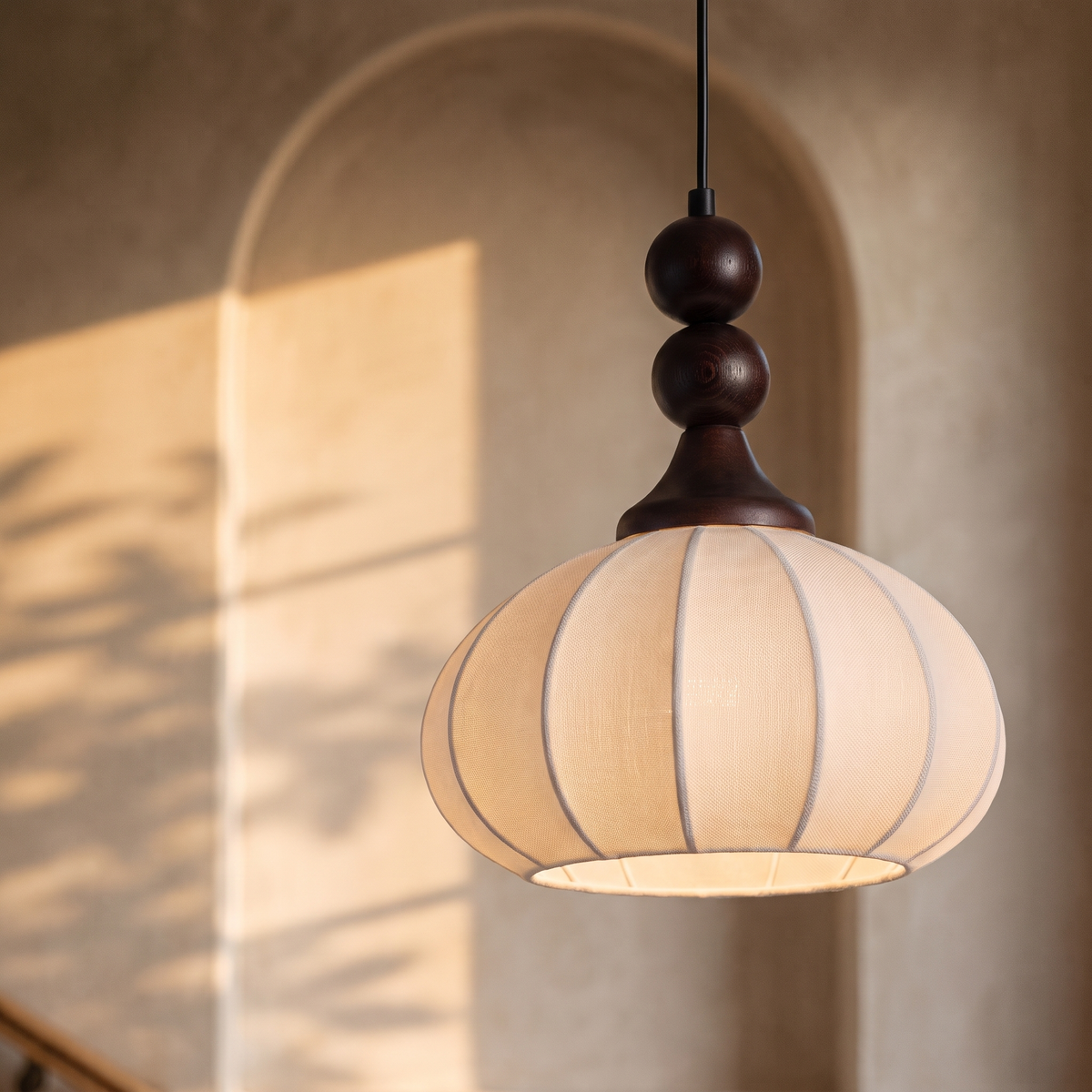 Lumeira ribbed silk and wood bead pendant light, lit in an arched alcove