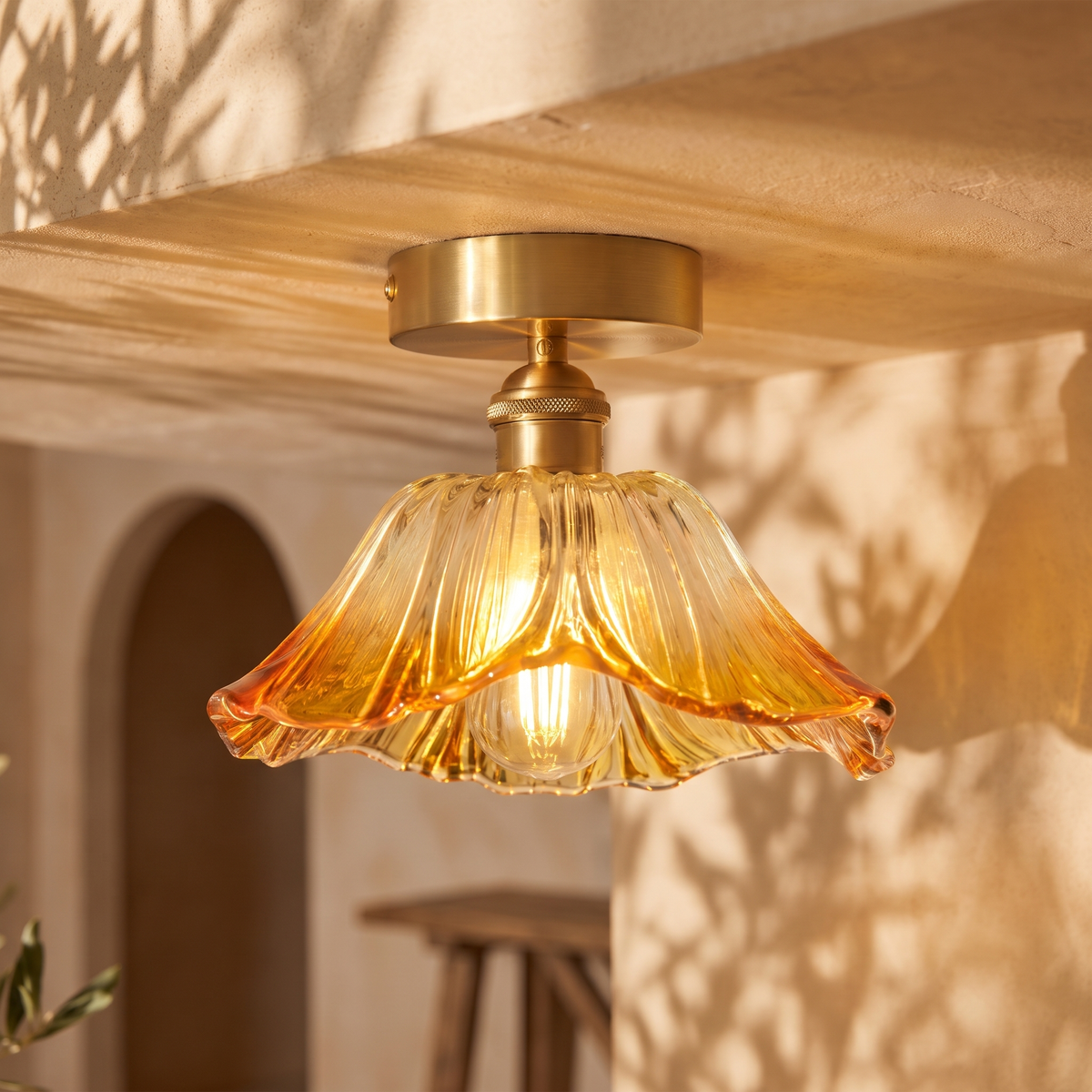Fiorella flush mount petal glass ceiling light in honey amber, lit above an arched entry hall doorway