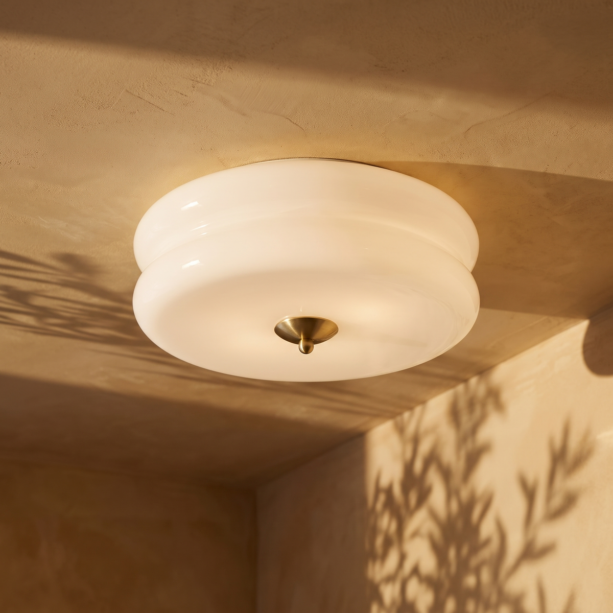 Deliona opal glass flush mount ceiling light in gold and white, lit on a plaster ceiling