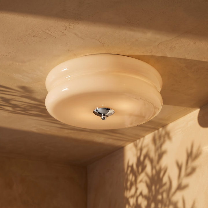 Deliona opal glass flush mount ceiling light in chrome and beige, lit on a plaster ceiling