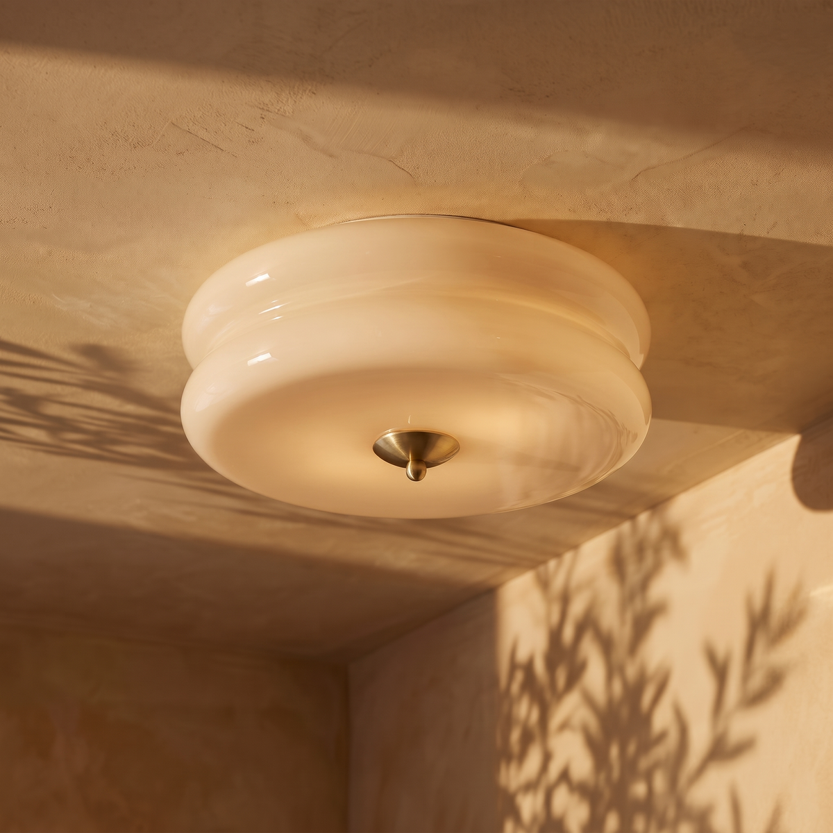 Deliona opal glass flush mount ceiling light in gold and beige, lit on a plaster ceiling