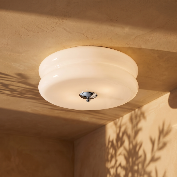 Deliona opal glass flush mount ceiling light in chrome and white, lit on a plaster ceiling