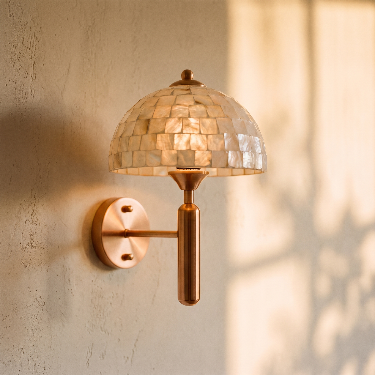 Perlassa mother of pearl wall sconce in gold, lit on a plaster wall