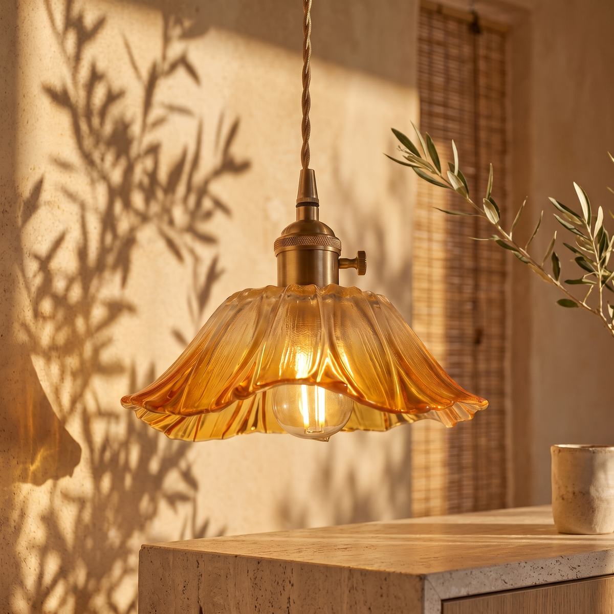 Fiorella petal glass cord pendant light in honey amber above a travertine kitchen island